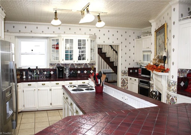 kitchen with pendant lighting, decorative backsplash, light tile patterned floors, white cabinetry, and stainless steel appliances