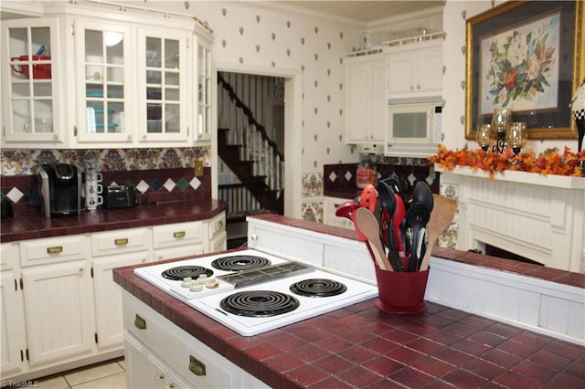 kitchen with tile patterned floors, tile countertops, white cabinetry, and white appliances