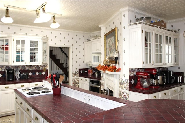 kitchen with pendant lighting, white gas stovetop, white cabinets, oven, and decorative backsplash