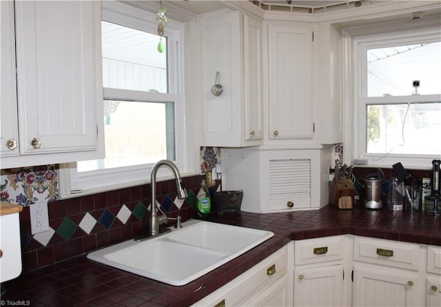 kitchen featuring tile countertops, white cabinetry, tasteful backsplash, and sink