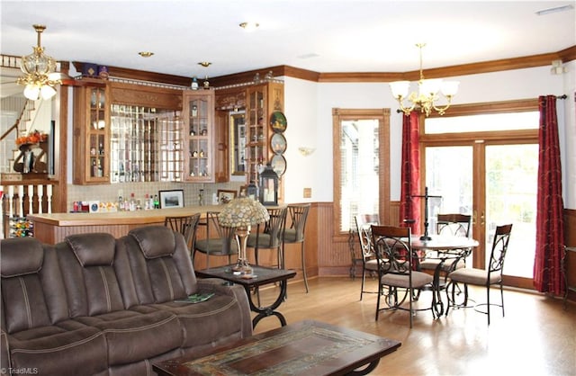 living room featuring french doors, light wood-type flooring, crown molding, and a notable chandelier