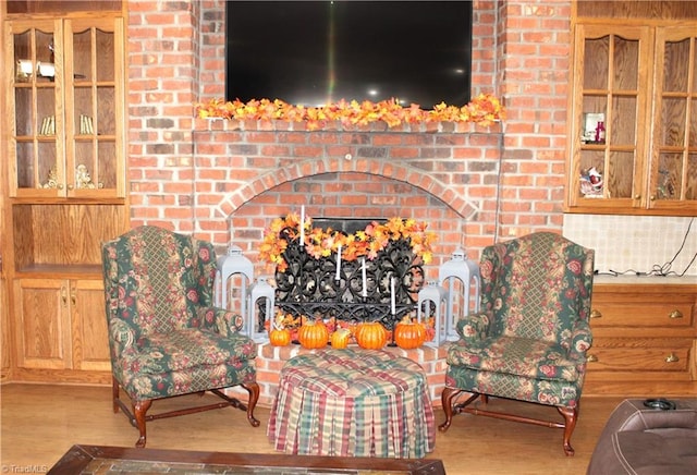 sitting room with light hardwood / wood-style floors and a brick fireplace