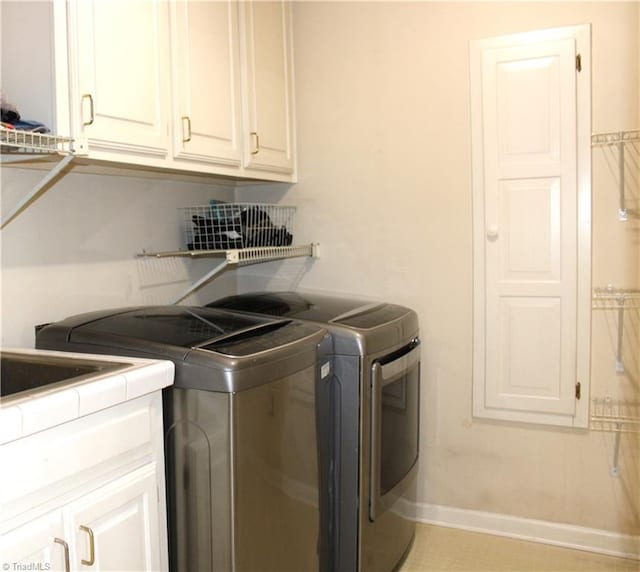 clothes washing area featuring cabinets and washing machine and dryer