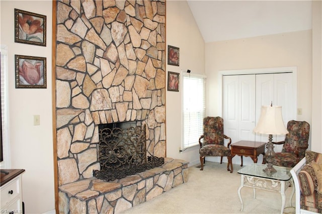 carpeted living room featuring vaulted ceiling and a stone fireplace