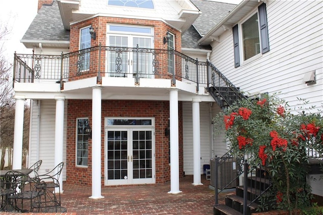 rear view of house featuring central AC, a patio area, a balcony, and french doors