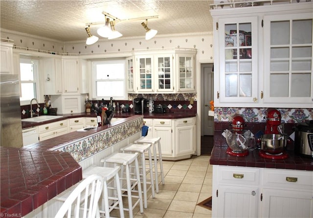 kitchen with plenty of natural light, white cabinets, light tile patterned flooring, and sink