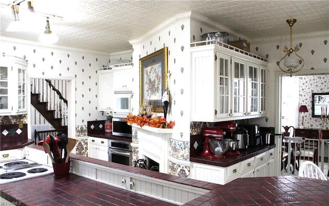 kitchen with white cabinetry, stainless steel oven, white stovetop, backsplash, and pendant lighting