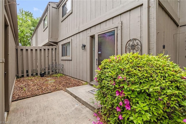 property entrance with a patio, board and batten siding, and fence