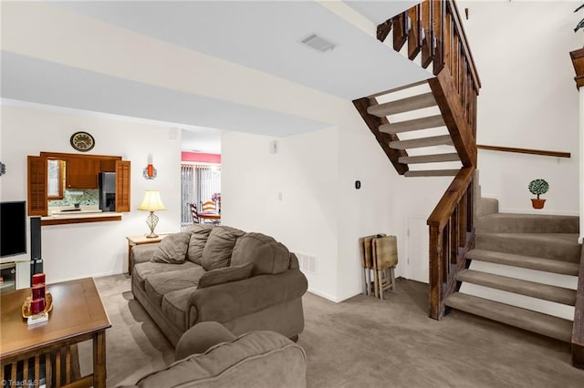 living area with light carpet, stairs, and visible vents