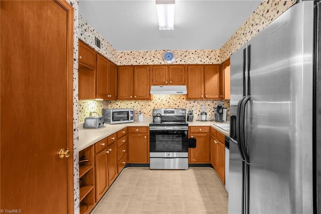 kitchen featuring light countertops, appliances with stainless steel finishes, under cabinet range hood, and brown cabinets