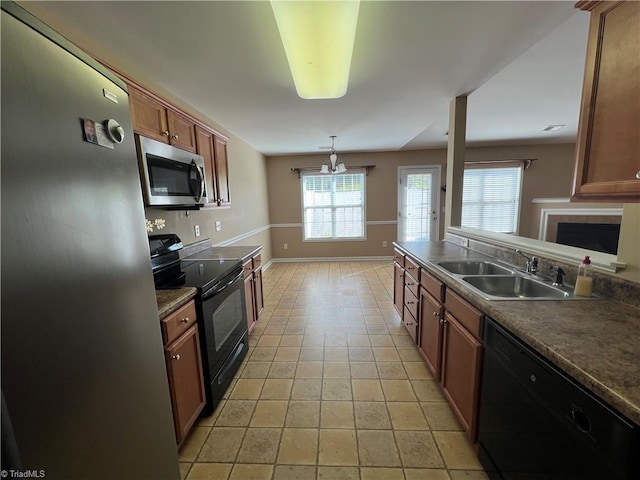 111 Braewyck Ln, King, NC 27021 - kitchen featuring black appliances, dark countertops, a fireplace, brown cabinetry, and pendant lighting