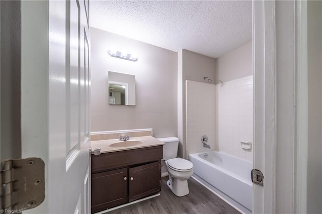 full bathroom featuring vanity, a textured ceiling, bathing tub / shower combination, hardwood / wood-style floors, and toilet