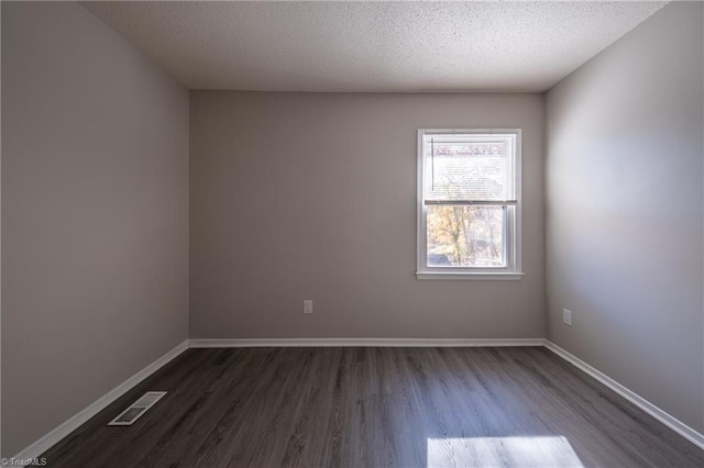 unfurnished room featuring dark wood-type flooring and a textured ceiling