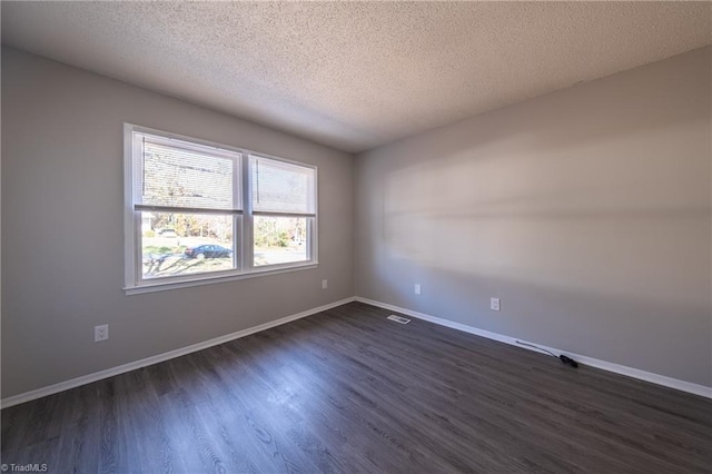 empty room with a textured ceiling and dark hardwood / wood-style flooring