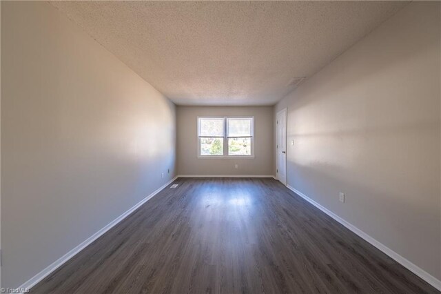 empty room with dark hardwood / wood-style flooring and a textured ceiling