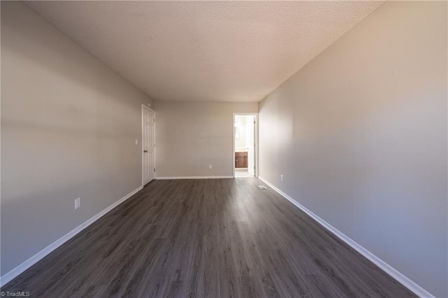 empty room featuring dark hardwood / wood-style flooring and a textured ceiling