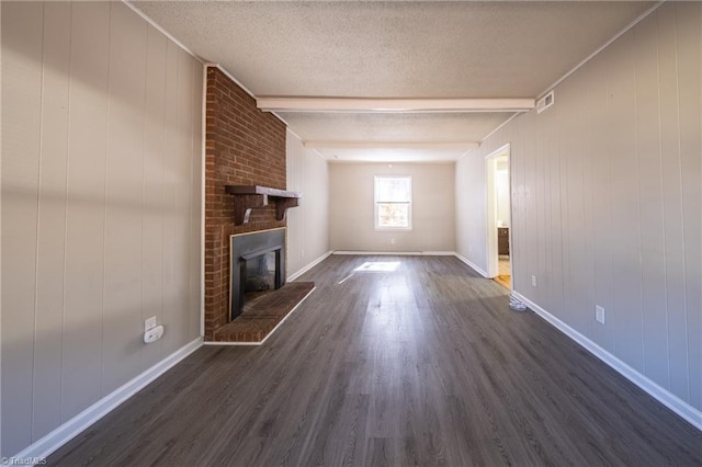 unfurnished living room featuring dark hardwood / wood-style flooring, a brick fireplace, a textured ceiling, wooden walls, and beamed ceiling