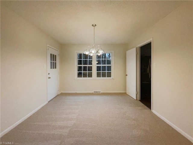 unfurnished room with a chandelier, light colored carpet, visible vents, and baseboards