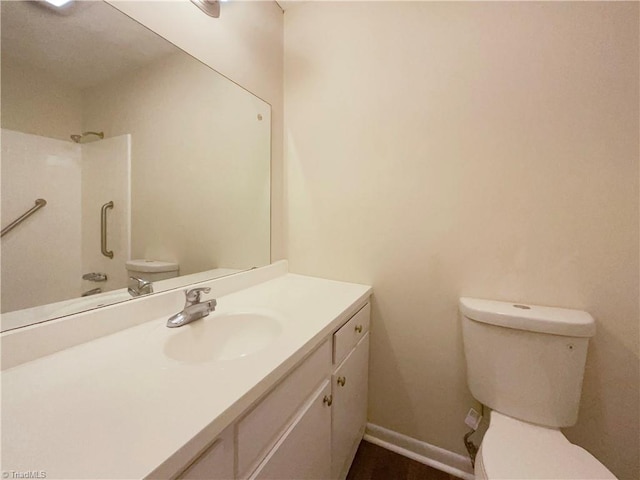 bathroom featuring baseboards, vanity, toilet, and walk in shower