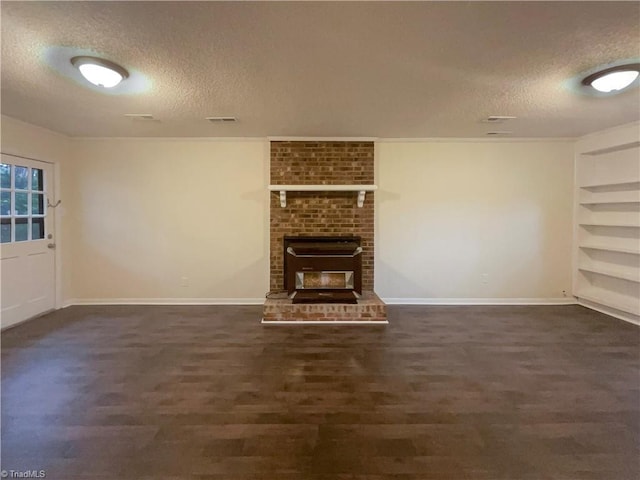 unfurnished living room featuring baseboards, built in shelves, visible vents, and a textured ceiling