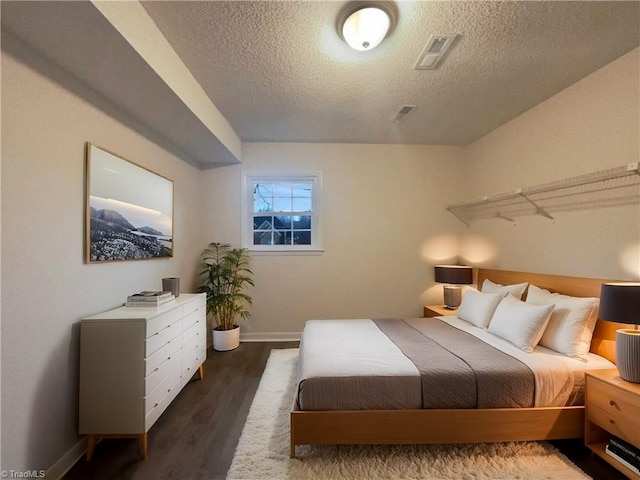 bedroom featuring a textured ceiling, wood finished floors, and baseboards