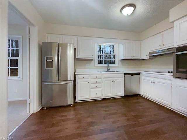 kitchen featuring stainless steel appliances, dark wood-style flooring, white cabinets, and a sink