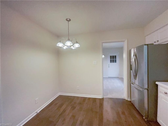 unfurnished dining area with baseboards, wood finished floors, and an inviting chandelier