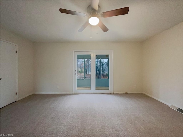 carpeted empty room featuring a ceiling fan, visible vents, and baseboards