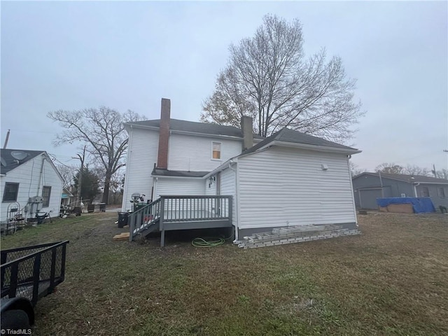 rear view of house featuring a lawn and a deck