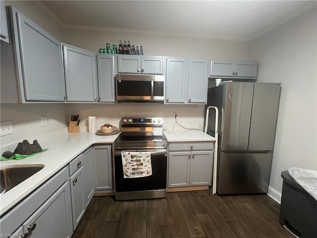 kitchen with appliances with stainless steel finishes, dark hardwood / wood-style floors, gray cabinets, and sink