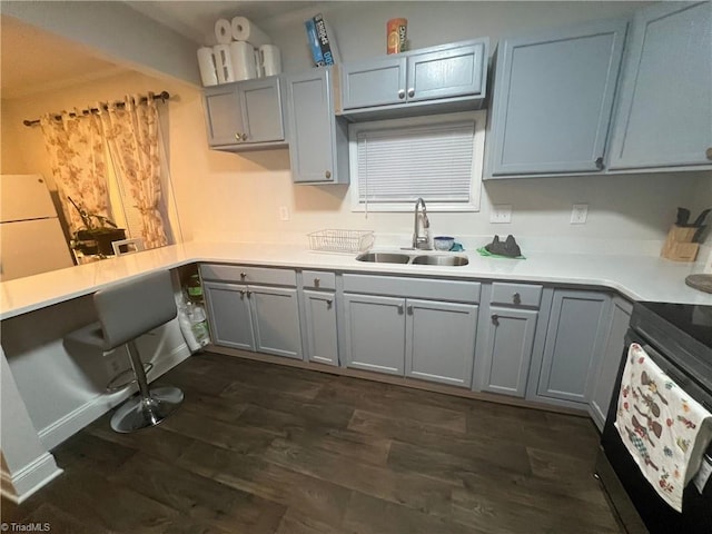 kitchen featuring dark wood-type flooring, sink, white refrigerator, gray cabinets, and stainless steel range with electric cooktop