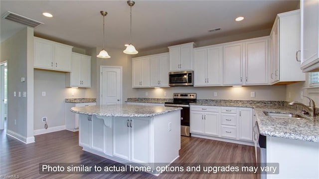 kitchen with stainless steel appliances, sink, a kitchen island, white cabinets, and dark wood-type flooring