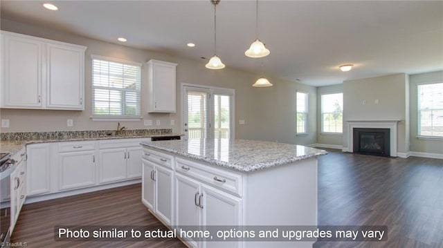 kitchen with white cabinetry, light stone counters, hanging light fixtures, a kitchen island, and dark wood-type flooring