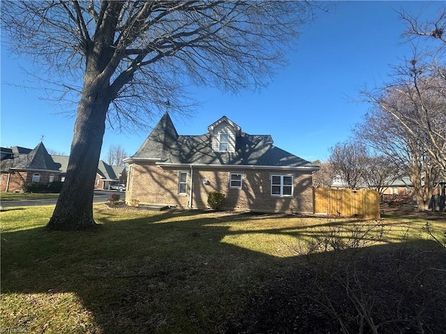 view of front of property featuring brick siding, fence, and a front lawn