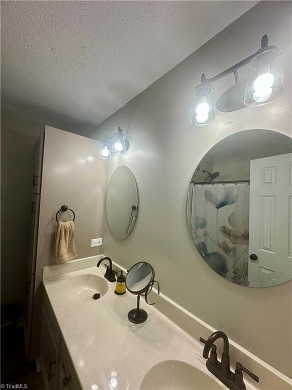 bathroom featuring a textured ceiling, double vanity, and a sink