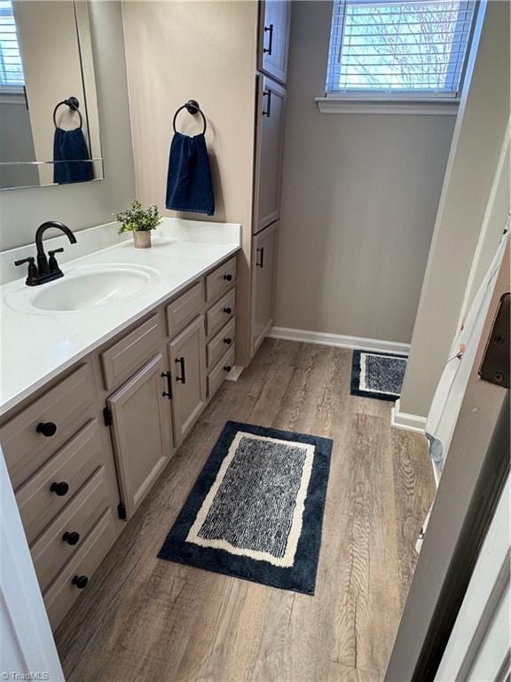 bathroom with a wealth of natural light, vanity, baseboards, and wood finished floors