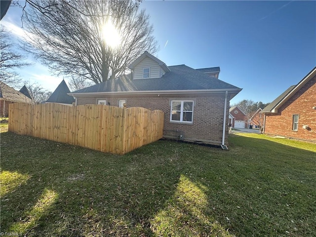 rear view of property with a yard, brick siding, and fence