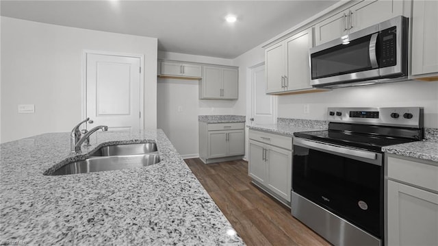 kitchen featuring dark wood-style flooring, light stone countertops, stainless steel appliances, and a sink