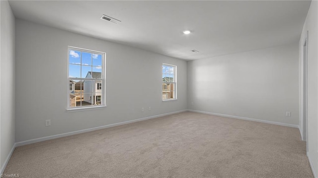 spare room featuring visible vents, light carpet, and baseboards