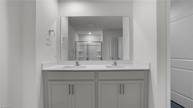 full bath featuring double vanity, a shower stall, and a sink