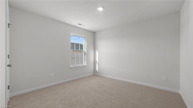 unfurnished room featuring visible vents, light colored carpet, and baseboards