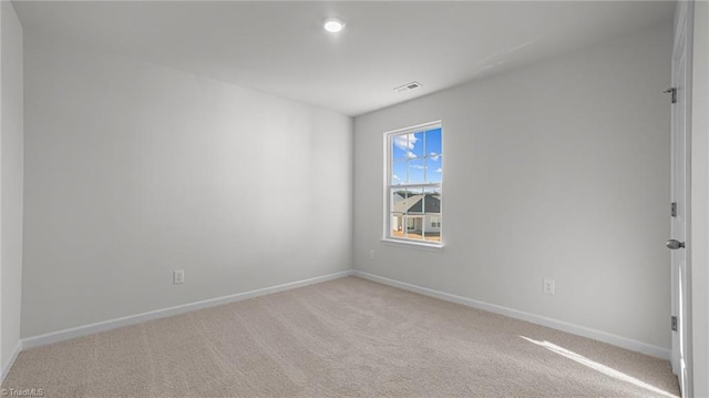 empty room featuring visible vents, light carpet, and baseboards