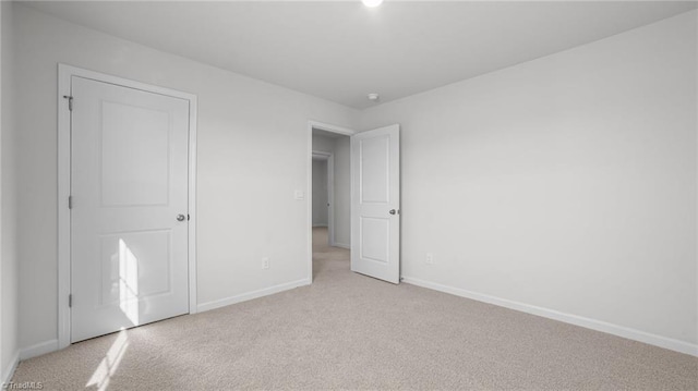 unfurnished bedroom featuring baseboards and light colored carpet