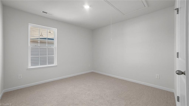 carpeted empty room featuring attic access, baseboards, and visible vents