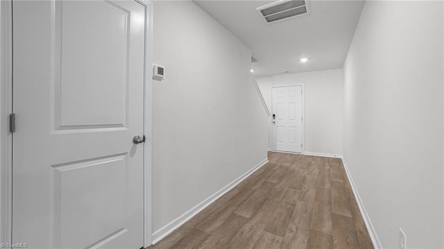 corridor featuring wood finished floors, visible vents, and baseboards