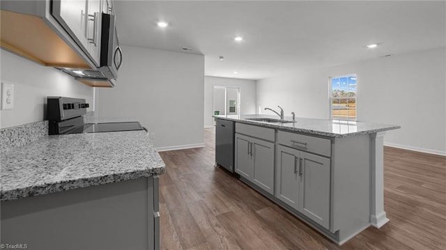 kitchen featuring a sink, gray cabinetry, dark wood finished floors, stainless steel appliances, and a kitchen island with sink