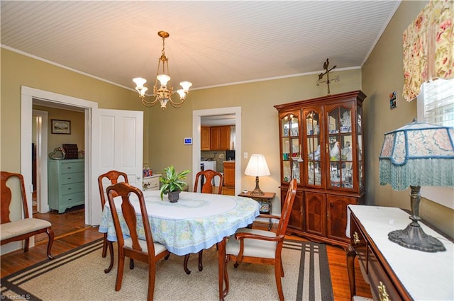 dining room featuring a notable chandelier, washing machine and dryer, crown molding, and wood finished floors