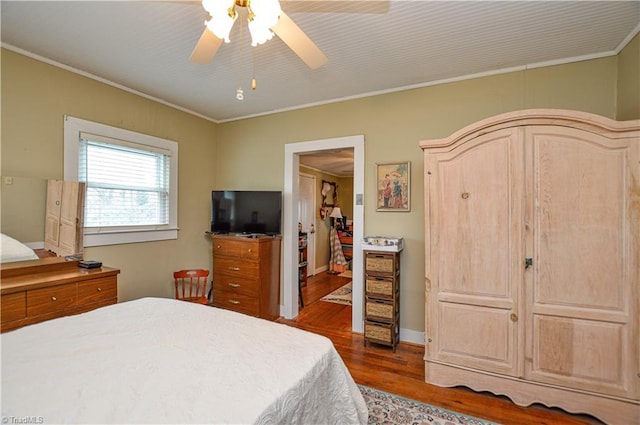 bedroom with ornamental molding, ceiling fan, and dark wood-style flooring