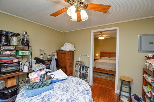 bedroom featuring electric panel, ornamental molding, ceiling fan, and wood finished floors