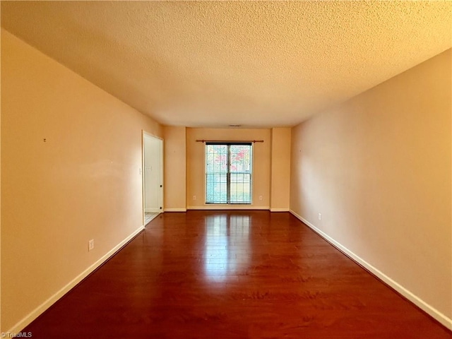 empty room with a textured ceiling and dark hardwood / wood-style floors